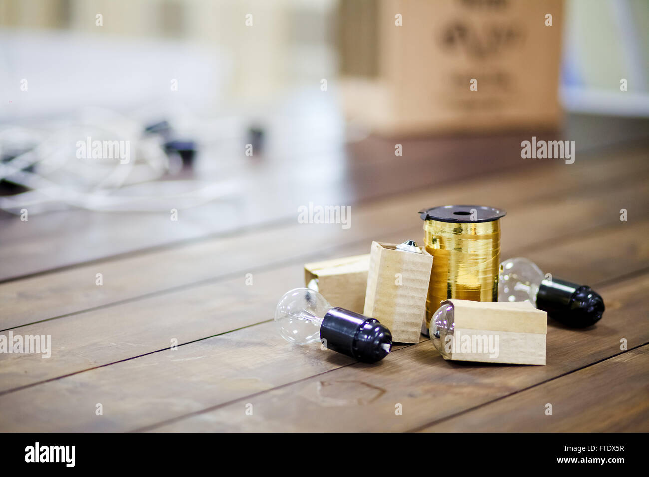 Diy decorating of events, incandescent bulbs with golden ribbon coil on wooden table. Copy space. Stock Photo