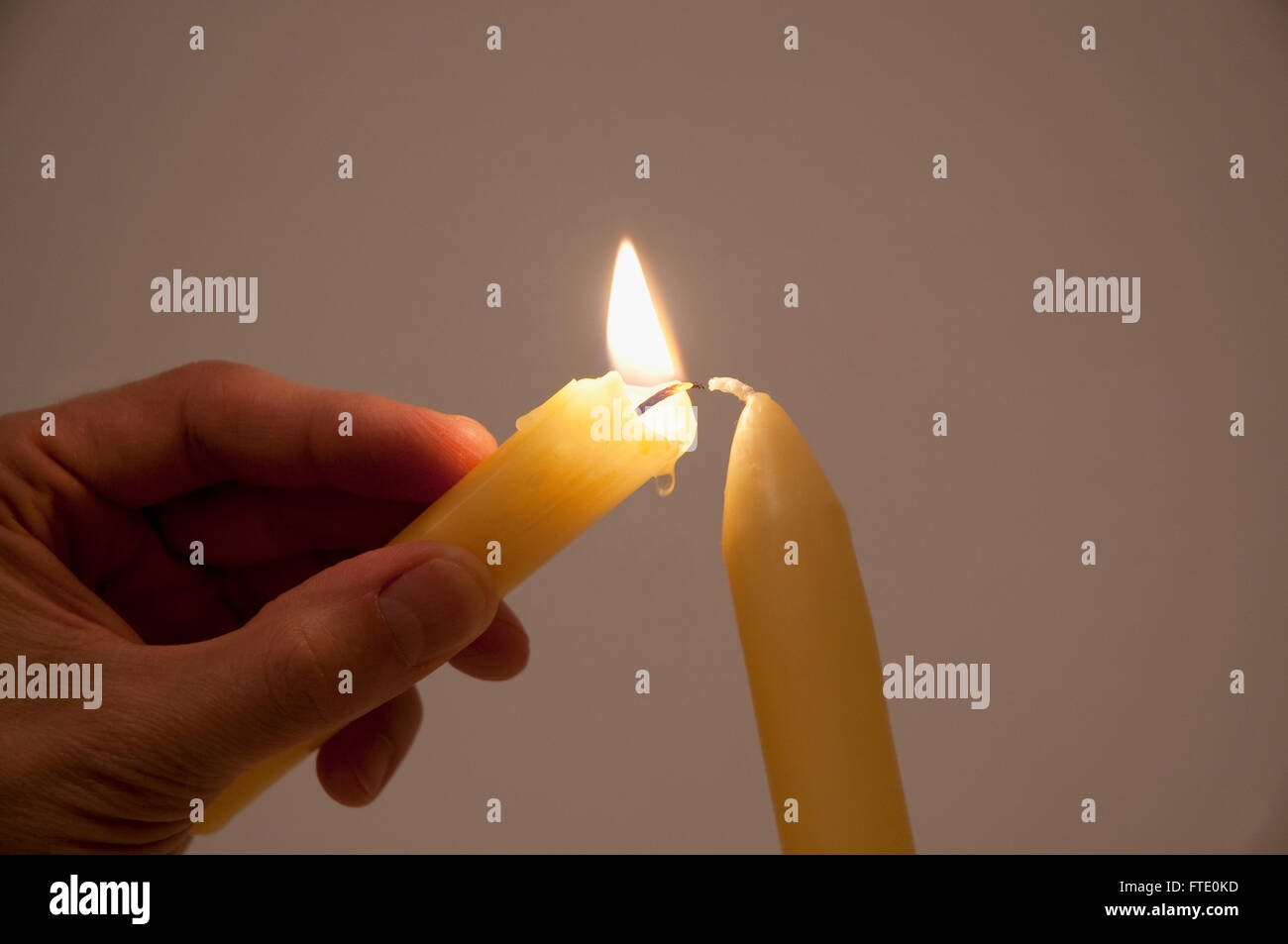 Man's hand lighting a new candle with a burning candle. Close view
