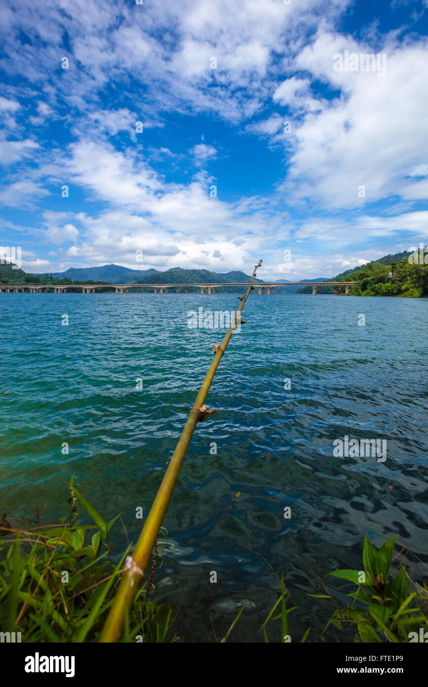 Fishing rod made of tree branch at a tropical lake and islands in cloudy blue sky. Belum resort, Banding, Temenggor Lake. Malays Stock Photo