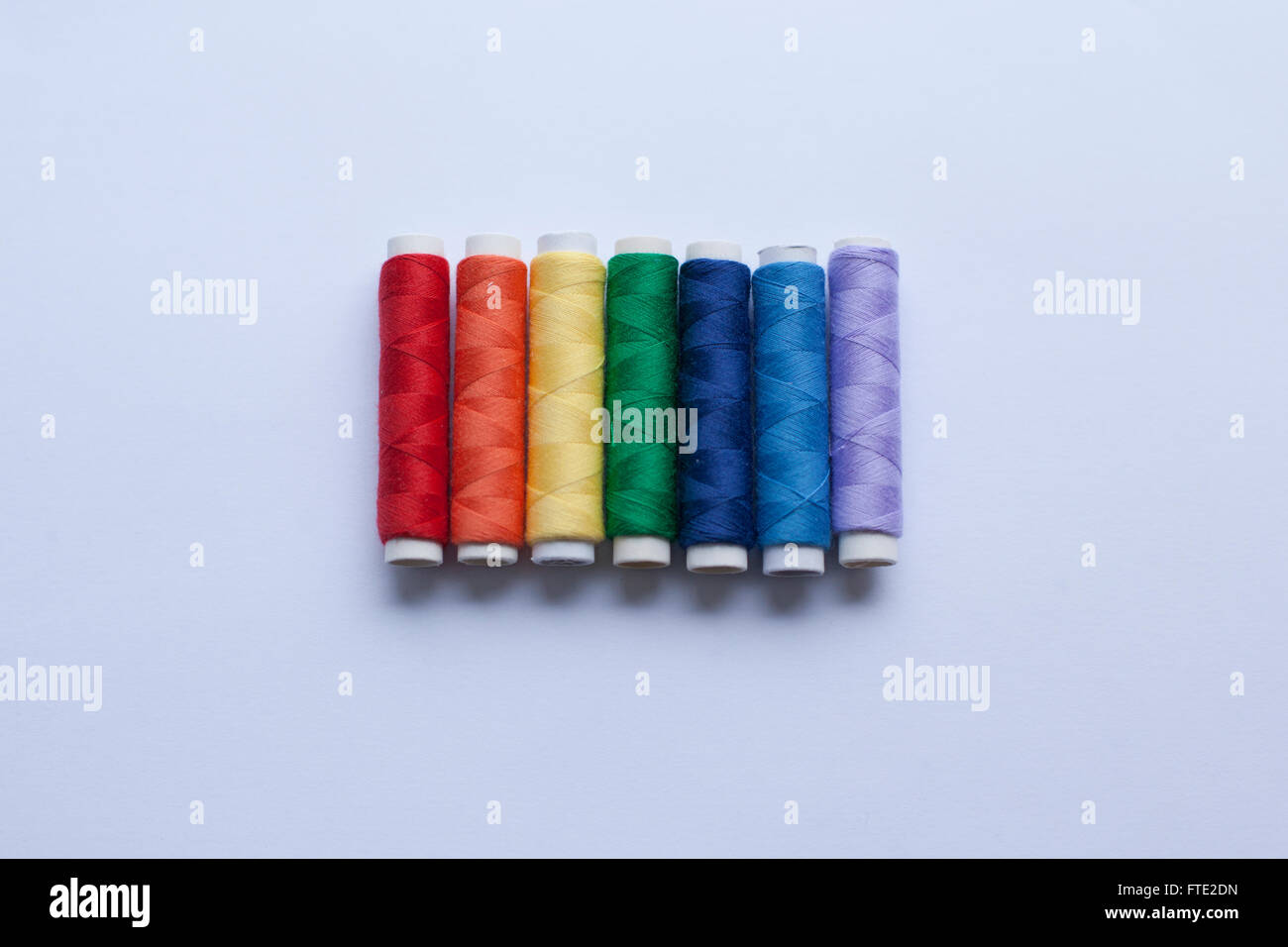 Colourful thread in the colours of the rainbow arranged on a white background Stock Photo