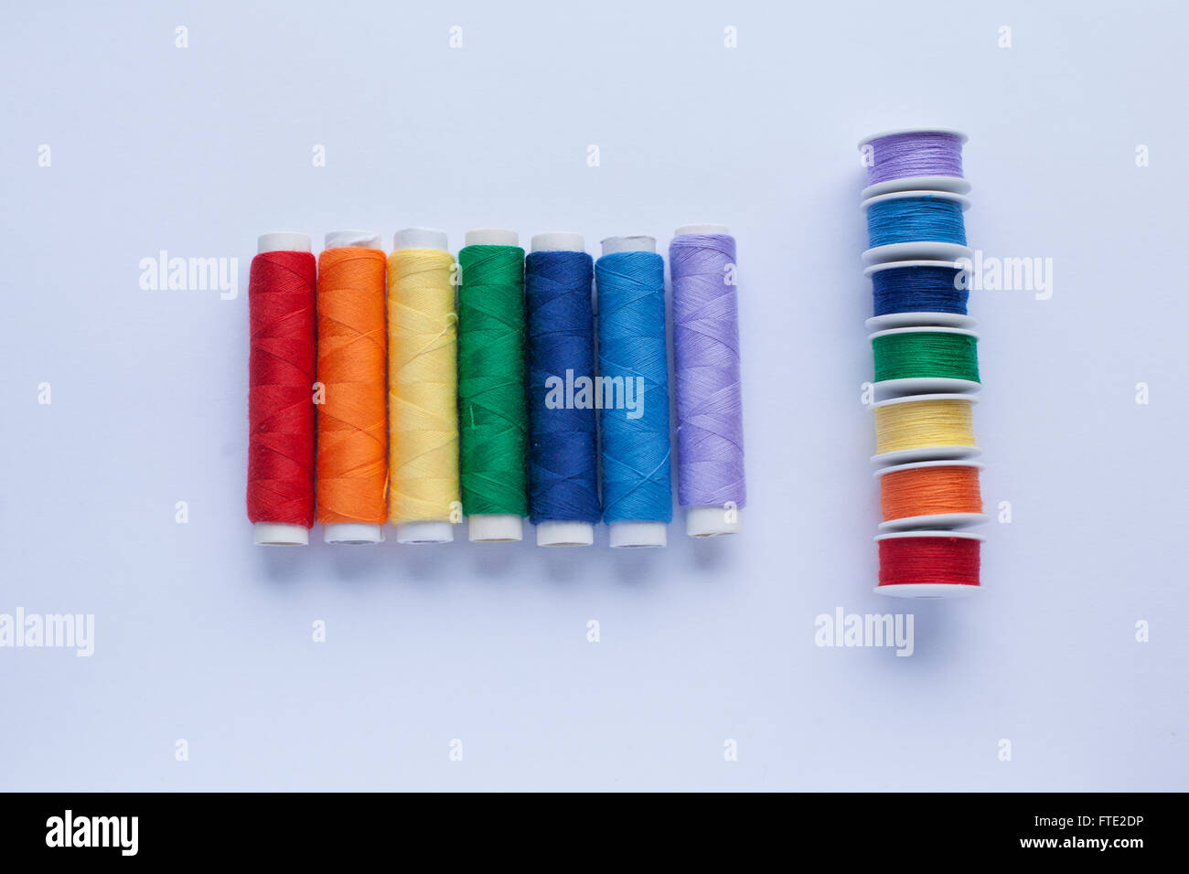 Colourful thread in the colours of the rainbow arranged on a white ...