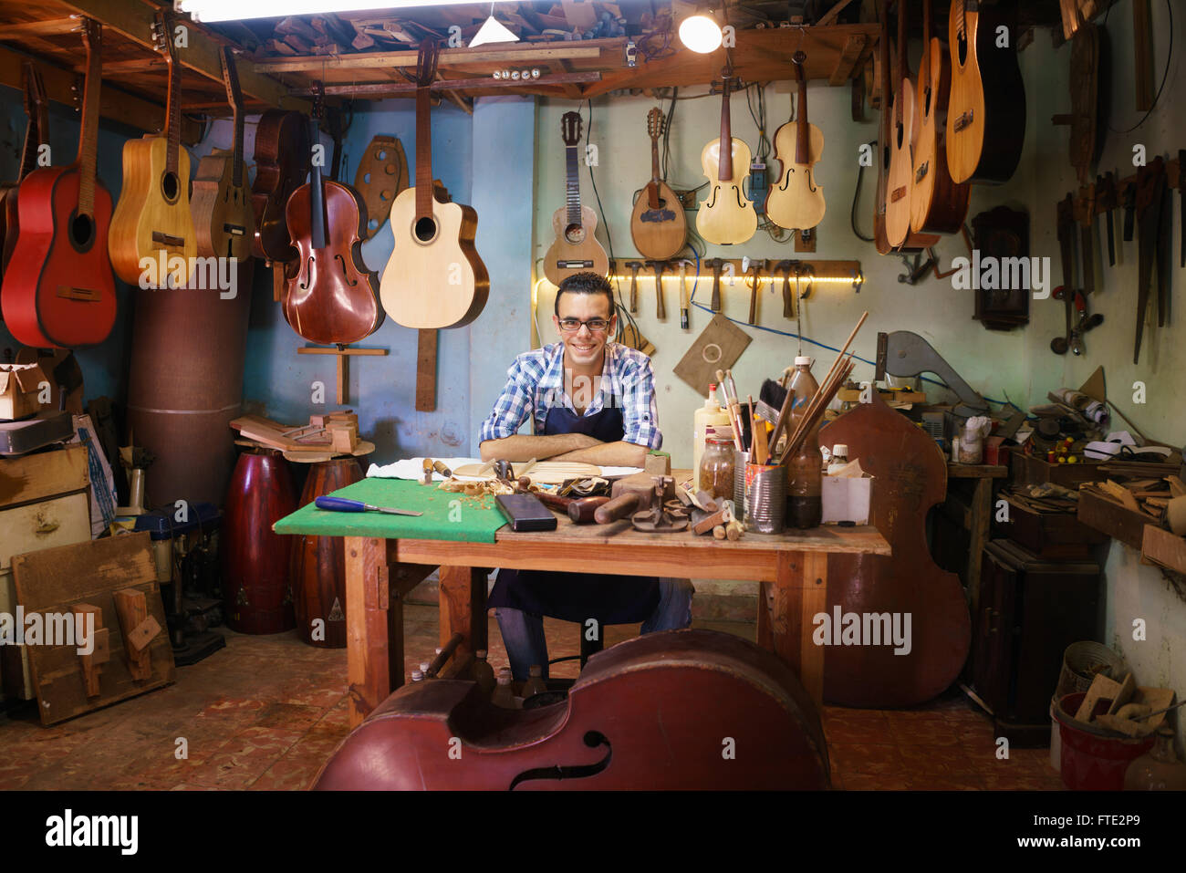 Lute maker shop and acoustic music instruments: portrait of a young adult  artisan sitting at his desk and smiling at camera. He Stock Photo - Alamy