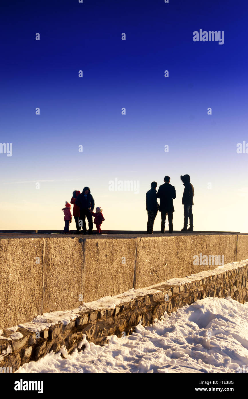 Groups of people stand on the edge of the horizon in a colour abstract image of men and women in a unique environment. Clear sky Stock Photo