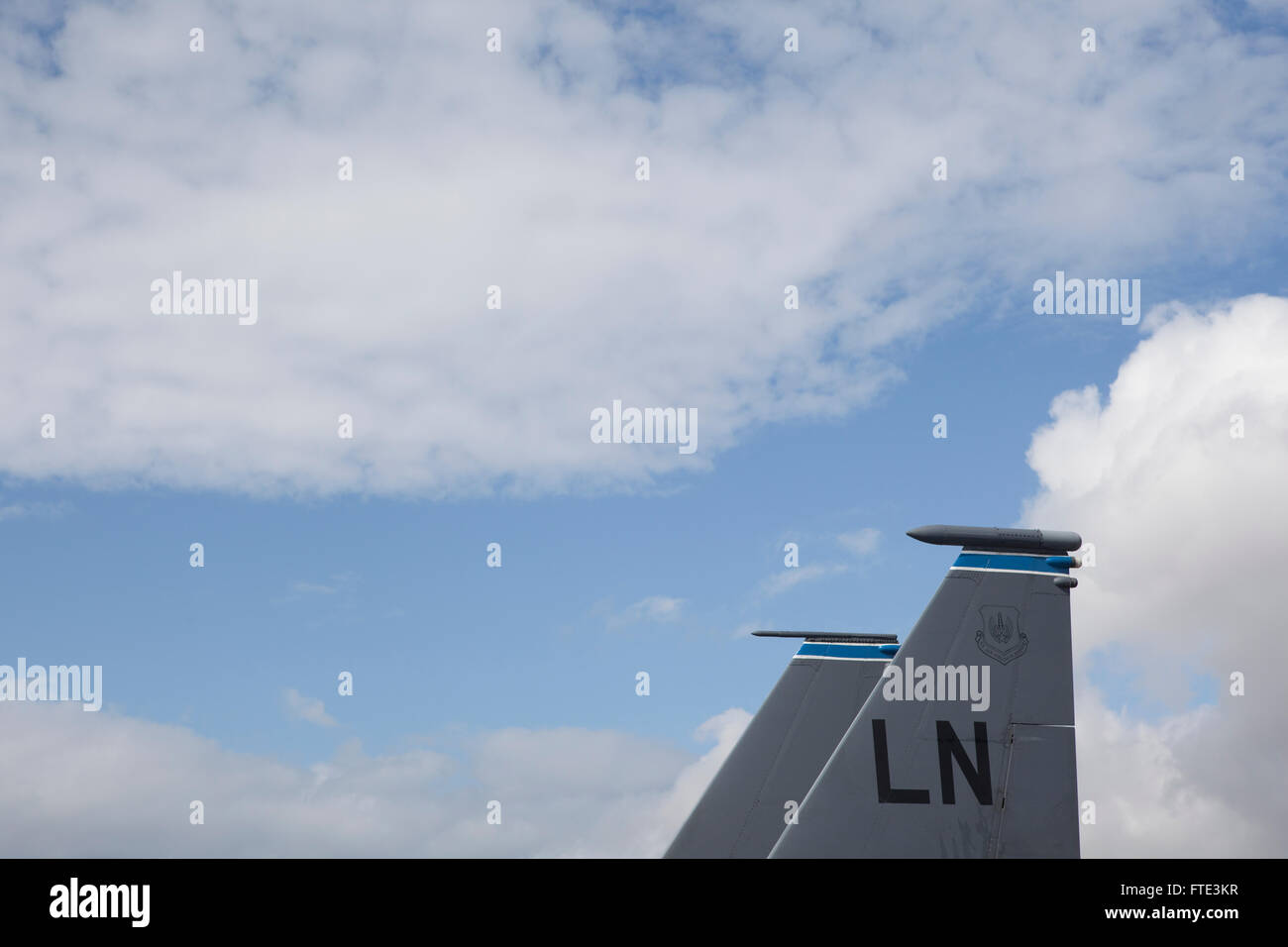 The tail of an aeroplane or fighter aircraft as it sits on the runway at a static display, showing ther typical grey livery and identification markings. Stock Photo