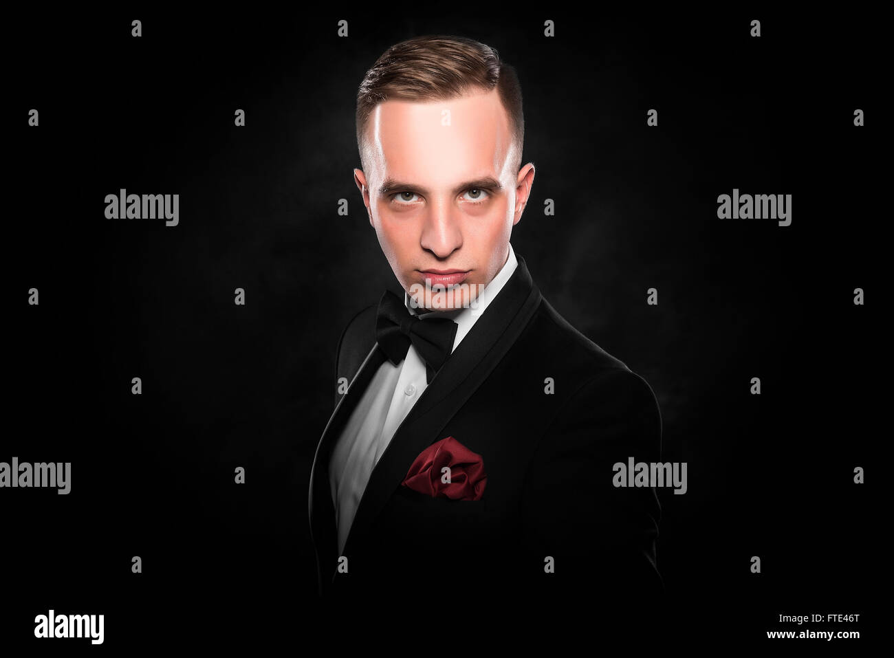 Young handsome man in black suit on dark background Stock Photo - Alamy