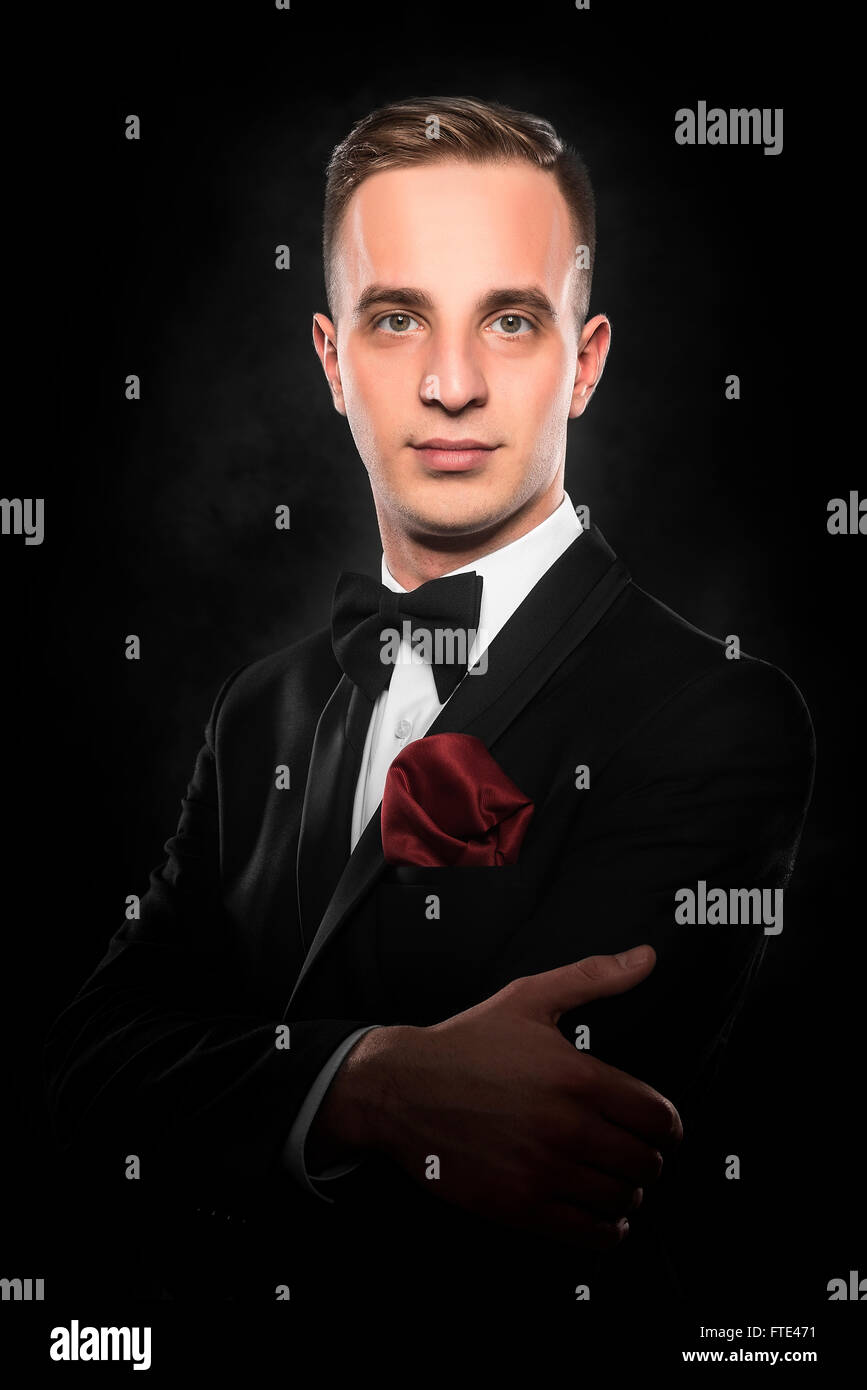 Young handsome man in black suit on dark background Stock Photo - Alamy