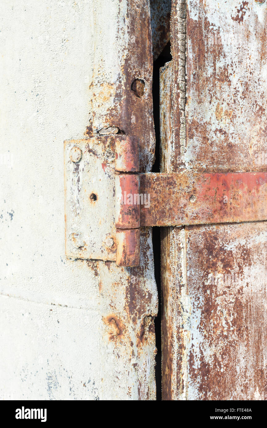 Old rusty metal door hinge using orange and gray colours. Copy space area for antique grunge