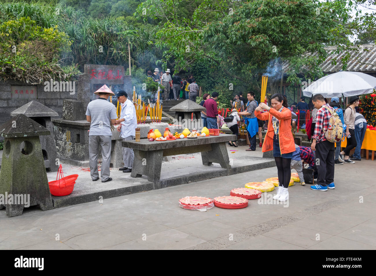 Young Chinese woman praying with burning incense sticks in her hand in