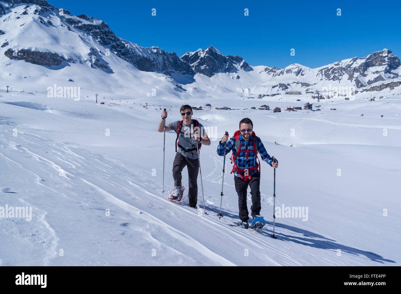 Two male snowshoe hikers hiking on a sunny winter day in the Swiss Alps. Melchsee-Frutt, Canton of Obwalden, Switzerland. Stock Photo