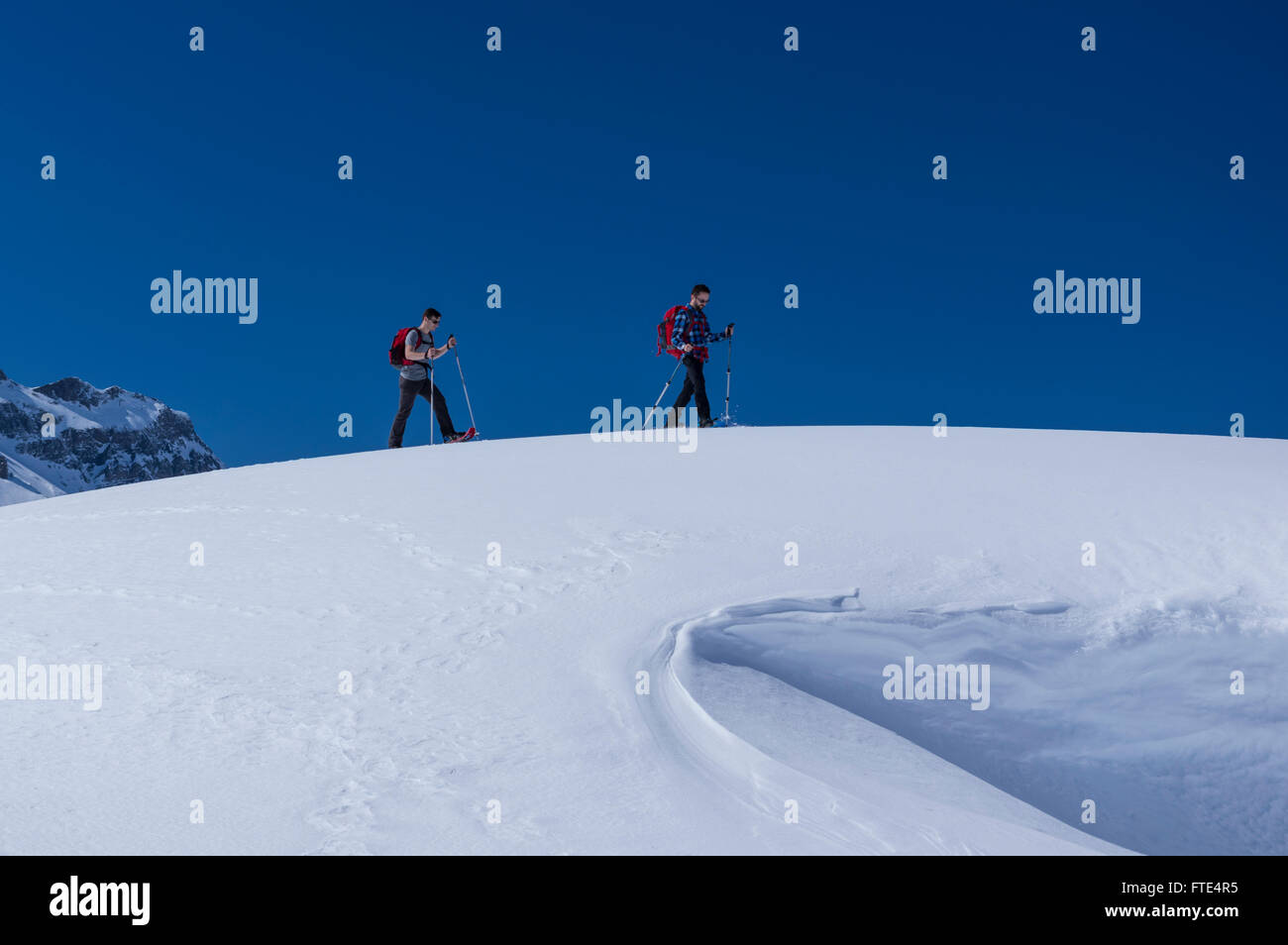 Two male snowshoe hikers hiking on a sunny winter day in the Swiss Alps. Melchsee-Frutt, Canton of Obwalden, Switzerland. Stock Photo