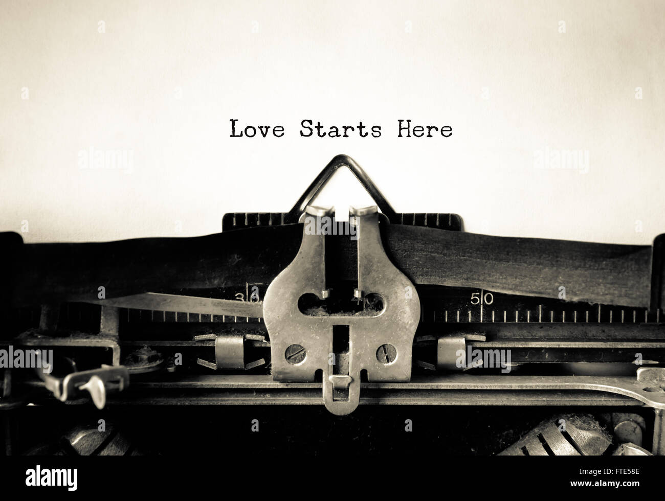 Love Starts Here word typed on a Vintage Typewriter. Stock Photo