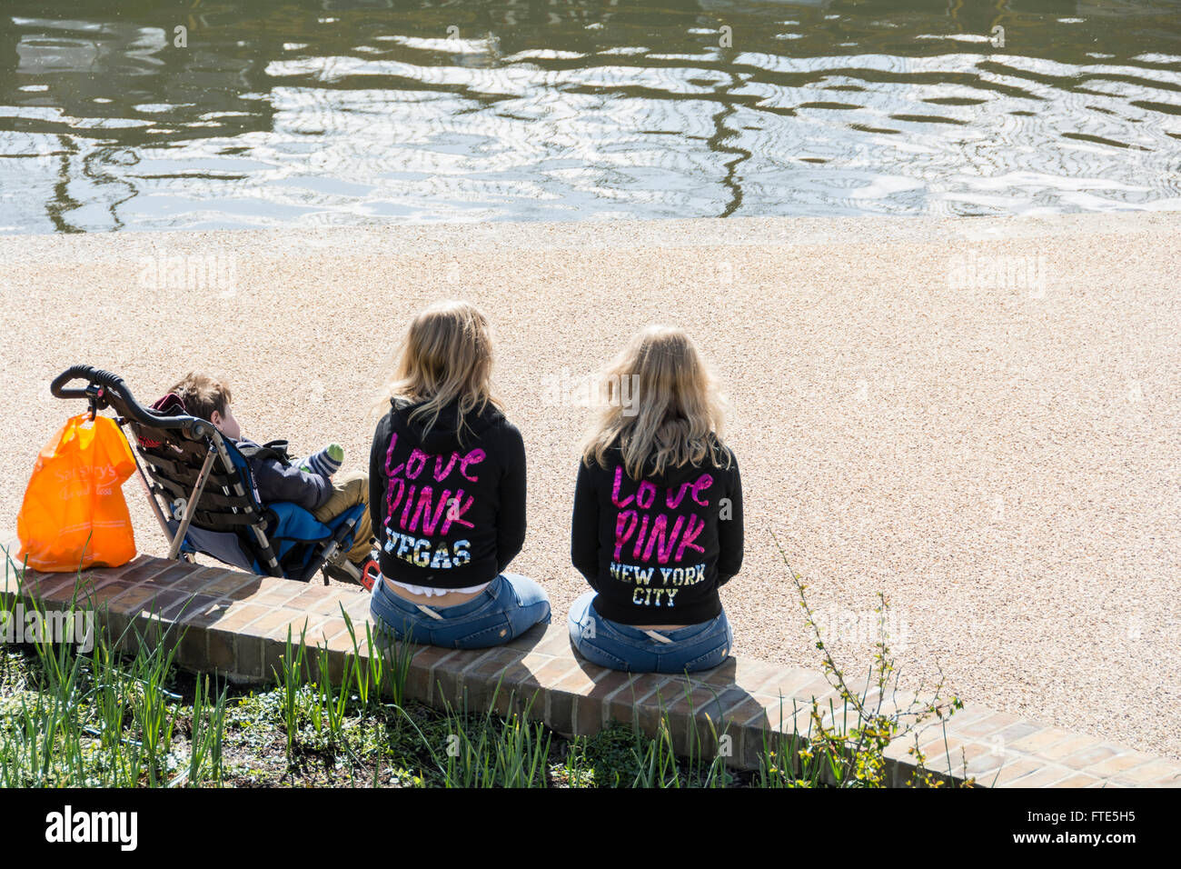 Two 'Love Pink' twin sisters sitting alongside Regent's Canal in London's King's Cross Granary Square Development Stock Photo