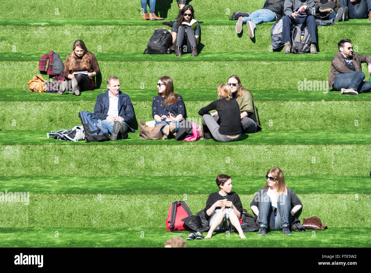 Millennials relaxing in Granary Square, King's Cross, near the Regent's Canal, London, England, UK Stock Photo