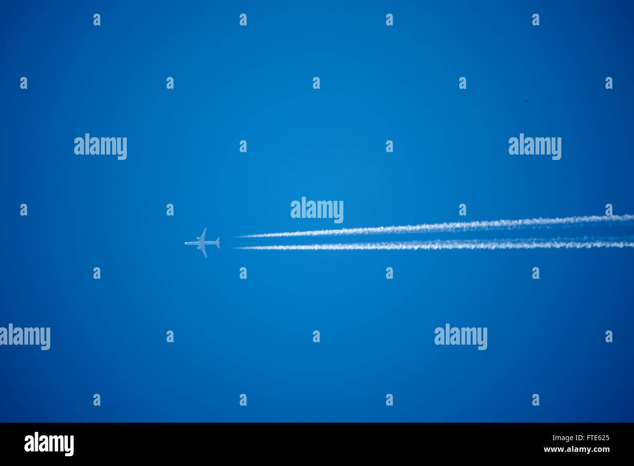 jet airliner streaking across blue sky Stock Photo
