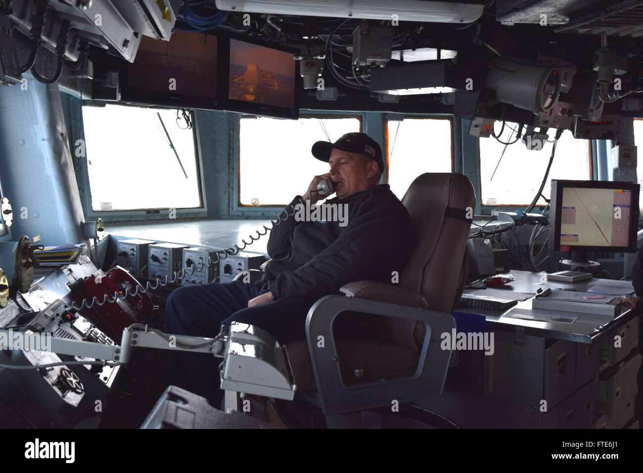 151112-N-ZZ999005 ATLANTIC OCEAN (Nov. 12, 2015) USS Carney (DDG 64) Commanding Officer, Cmdr. Ken Pickard, from Pensacola, Florida, receives tactical updates via a bridge phone Nov. 12, 2015. Carney, an Arleigh Burke-class guided-missile destroyer, forward deployed to Rota, Spain is conducting a routine patrol in the U.S. 6th Fleet area of operations in support of U.S. national security interests in Europe. (U.S. Navy photo by Lt. j.g. Eva LaFiura/ Released) Stock Photo