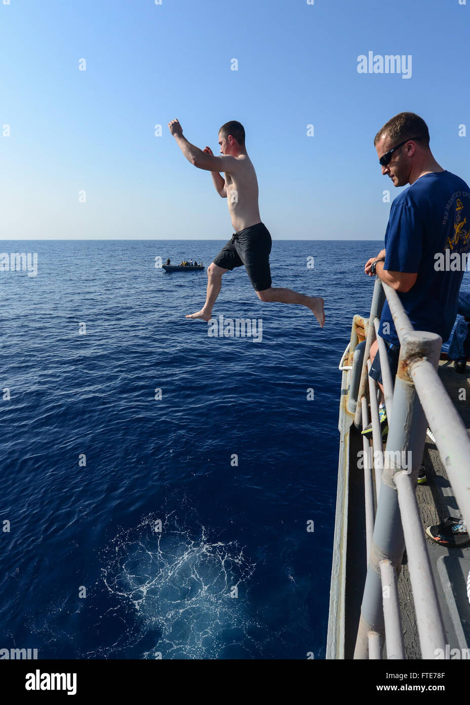 MEDITERRANEAN SEA (Nov. 3, 2013) - Operations Specialist 3rd Class Brian Caddell jumps from the fantail while Senior Chief Hospital Corpsman Andrea Zoto observes during a swim call aboard the guided missile cruiser USS Monterey (CG 61). Monterey is deployed in support of maritime security operations and theater security cooperation efforts in the U.S. 6th Fleet area of operations. (U.S. Navy photo by Mass Communication Specialist 3rd Class Billy Ho/Released) Stock Photo