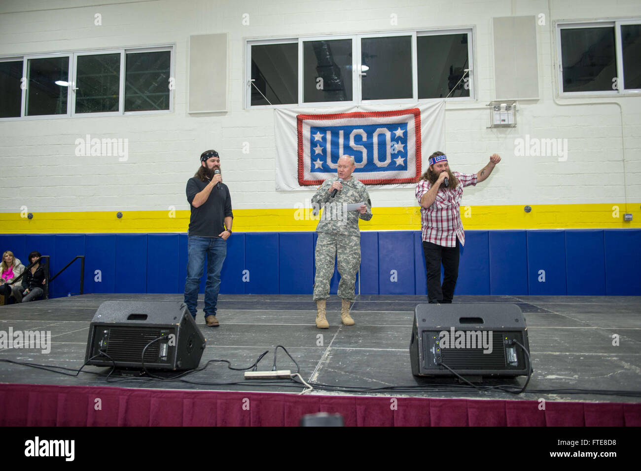 SOUDA BAY, Greece  (Dec. 08, 2013) -   'Duck Dynasty' stars Jep, left, and Willie Robertson, right, sing a christmas song with Chairman of the Joint Chiefs of Staff, Gen. Martin Dempsey, to Sailors, Marines, and Airman at Naval Support Activity (NSA) Souda Bay for the annual USO holiday tour, which features a variety of other celebrities and the Chairman of the Joint Chiefs of Staff visiting four countries and five bases to interact with the troops for the holidays.  Stout, homeported in Norfolk, Va., is on a scheduled deployment supporting maritime security operations and theater security coo Stock Photo