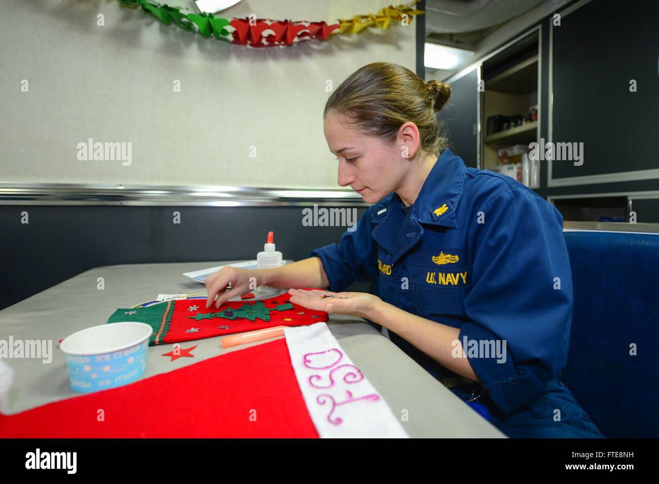 Lt. j.g. Kimberly Robillard, food service officer aboard USS Monterey (CG 61), decorates a Santa hat on the mess decks while the ship is deployed in the U.S. 6th Fleet, supporting maritime security and cooperation efforts. Stock Photo