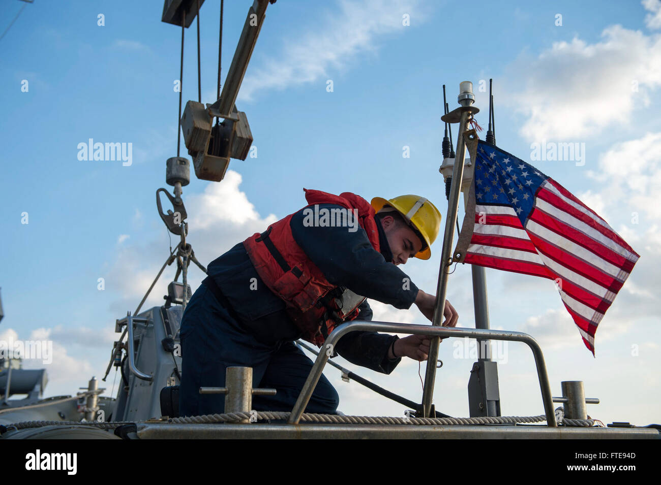 140111-N-UD469-028: MEDITERRANEAN SEA (Jan. 11, 2014) - Boatswain's Mate 3rd Class Kevin Greider hangs the national ensign on a rigid-hull inflatable boat aboard the Arleigh Burke-class guided-missile destroyer USS Stout (DDG 55) in preparation for a personnel transfer with the Military Sealift Command fleet replenishment oiler USNS Leroy Grumman (T-AO 195). Stout, homeported in Norfolk, Va., is on a scheduled deployment supporting maritime security operations and theater security cooperation efforts in the U.S. 6th Fleet area of operations. (U.S. Navy photo by Mass Communication Specialist 2n Stock Photo