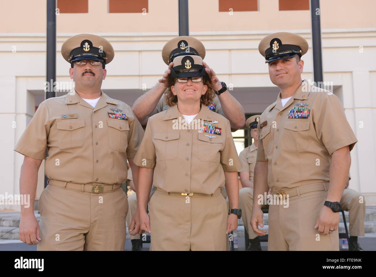 140916-N-OX801-170 NAPLES, ITALY (Sept. 16, 2014) Senior Chief Chris Carter places a chief petty officer (CPO) cover Chief Operations Specialist Amanda Doige during the U.S. Naval Forces Europe-Africa/U.S. 6th Fleet chief petty officer pinning ceremony at Naval Support Activity, Naples. The ceremony honored 28 Sailors promoted to the rank of chief petty officer, having their anchors pinned by friends, family and their new peers in the CPO Mess. (U.S. Navy photo by Mass Communication Specialist 3rd Class Daniel Schumacher/RELEASED) Stock Photo