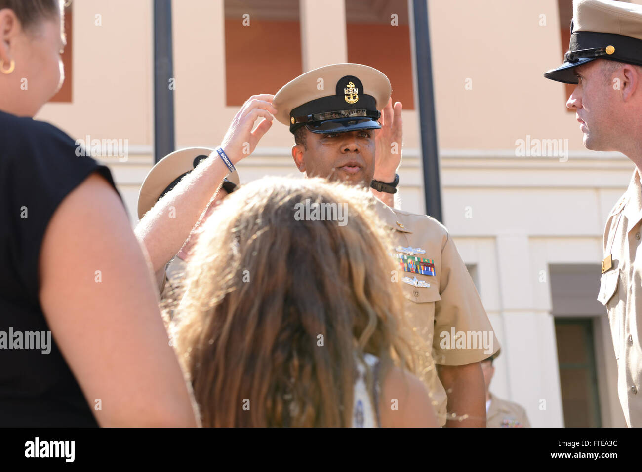 140916-N-OX801-251 NAPLES, ITALY (Sept. 16, 2014) Senior Chief Croughen places a chief petty officer (CPO) cover on Chief Information Systems Technician Frank Miller during the U.S. Naval Forces Europe-Africa/U.S. 6th Fleet chief petty officer pinning ceremony at Naval Support Activity, Naples. The ceremony honored 28 Sailors promoted to the rank of chief petty officer, having their anchors pinned by friends, family and their new peers in the CPO Mess. (U.S. Navy photo by Mass Communication Specialist 3rd Class Daniel Schumacher/RELEASED) Stock Photo