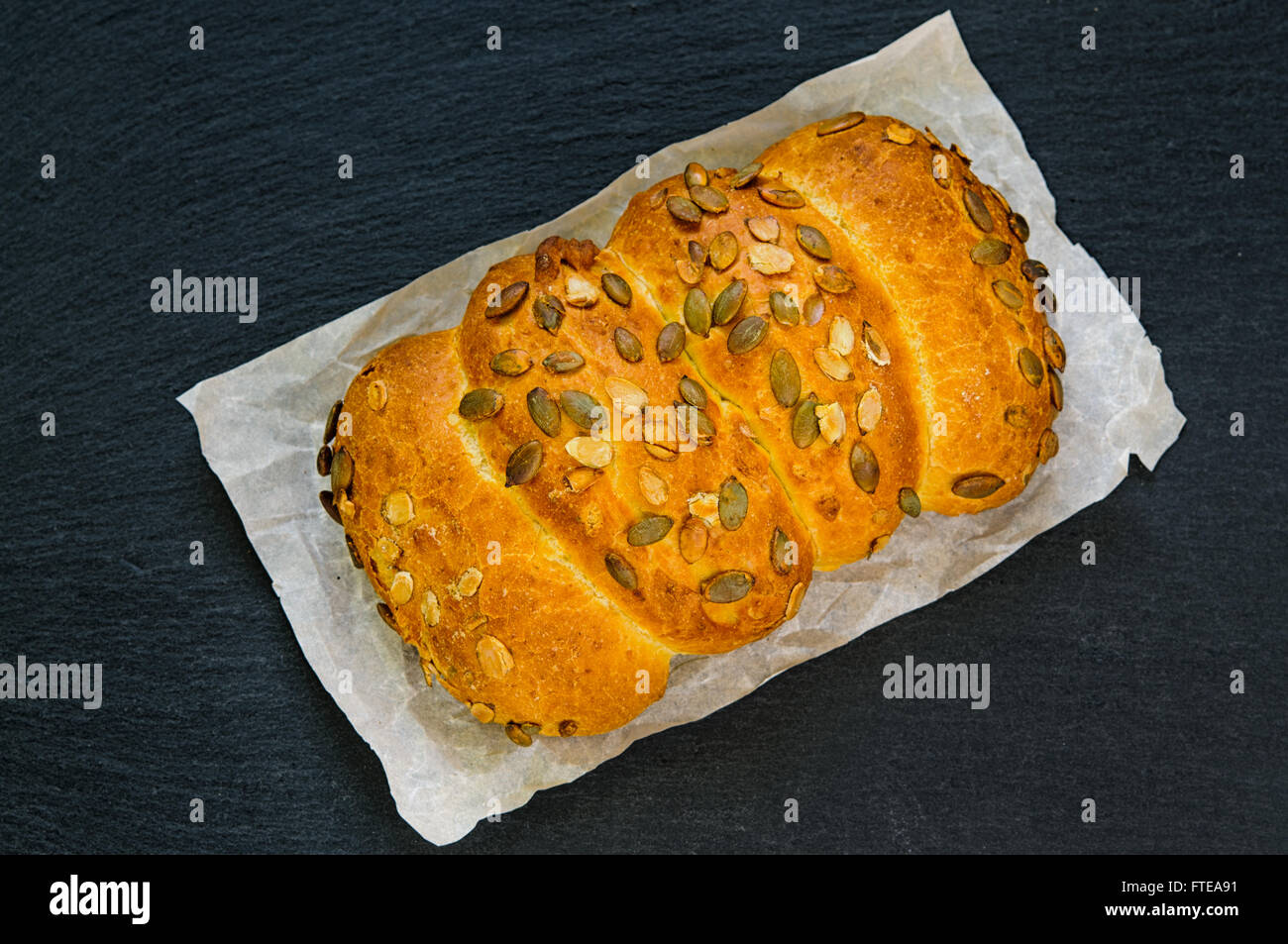 Top view of bread loaf with pumpkin seeds on black slate stone board Stock Photo