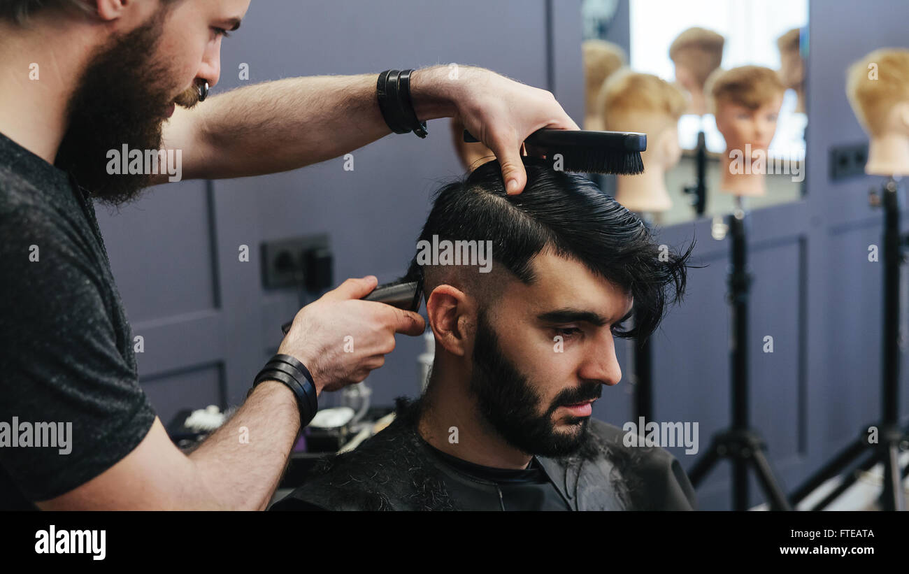 Male barber combing and shaving hair of a male client Stock Photo