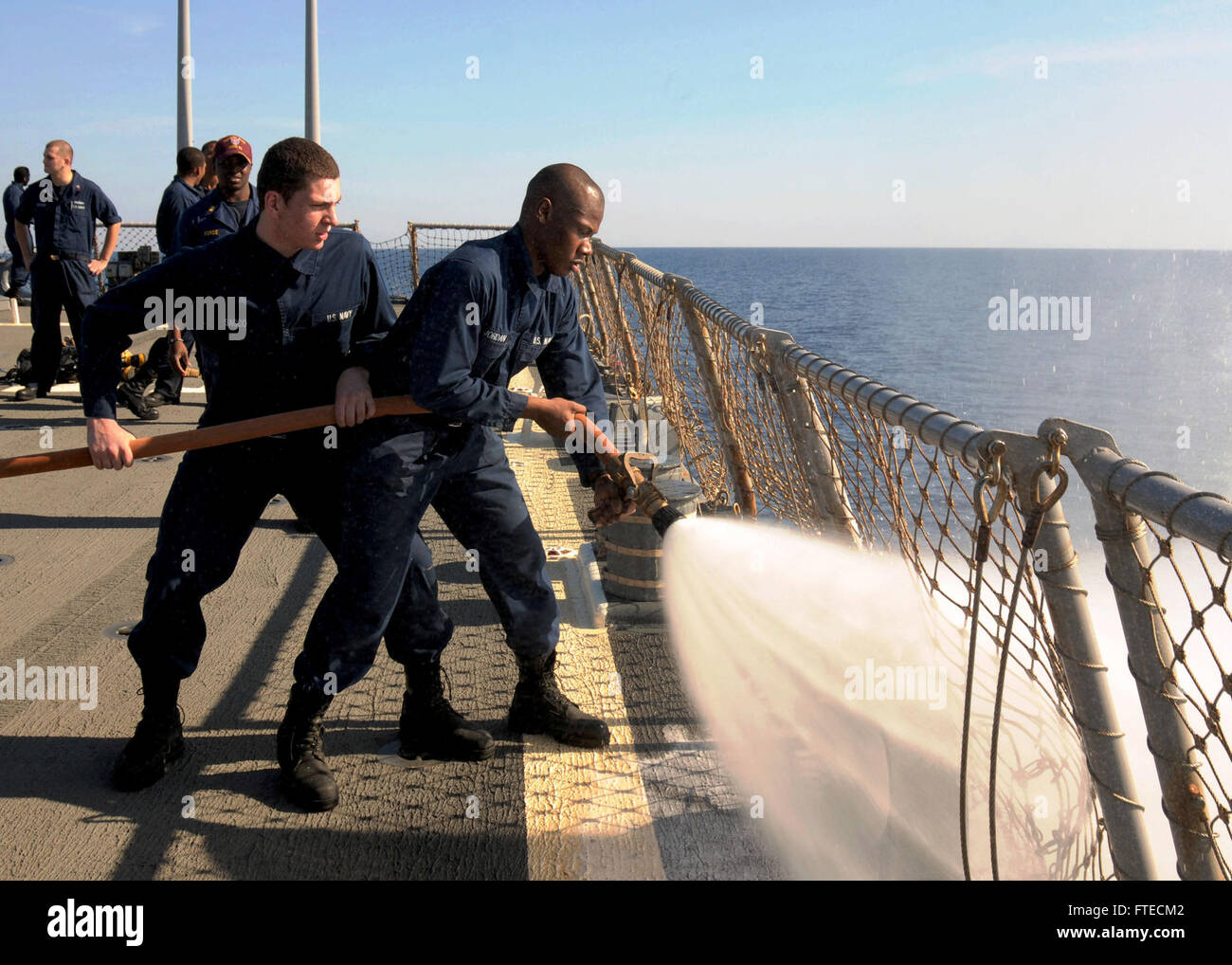 140323-N-CH661-014 MEDITERRANEAN SEA (March 22, 2014) - Hull Maintenance Technician Fireman Kwesi Jordan, right, and Damage Controlman Fireman Domenic Sacco, both assigned to the guided-missile destroyer USS Ramage (DDG 61), spray a fire hose during a timed event as a part of Damage Control Olympics. Ramage, homeported in Norfolk, Va., is on a scheduled deployment supporting maritime security operations and theater security cooperation efforts in the U.S. 6th Fleet area of operations. (U.S. Navy photo by Mass Communication Specialist 2nd Class Jared King/Released)   Join the conversation on Tw Stock Photo