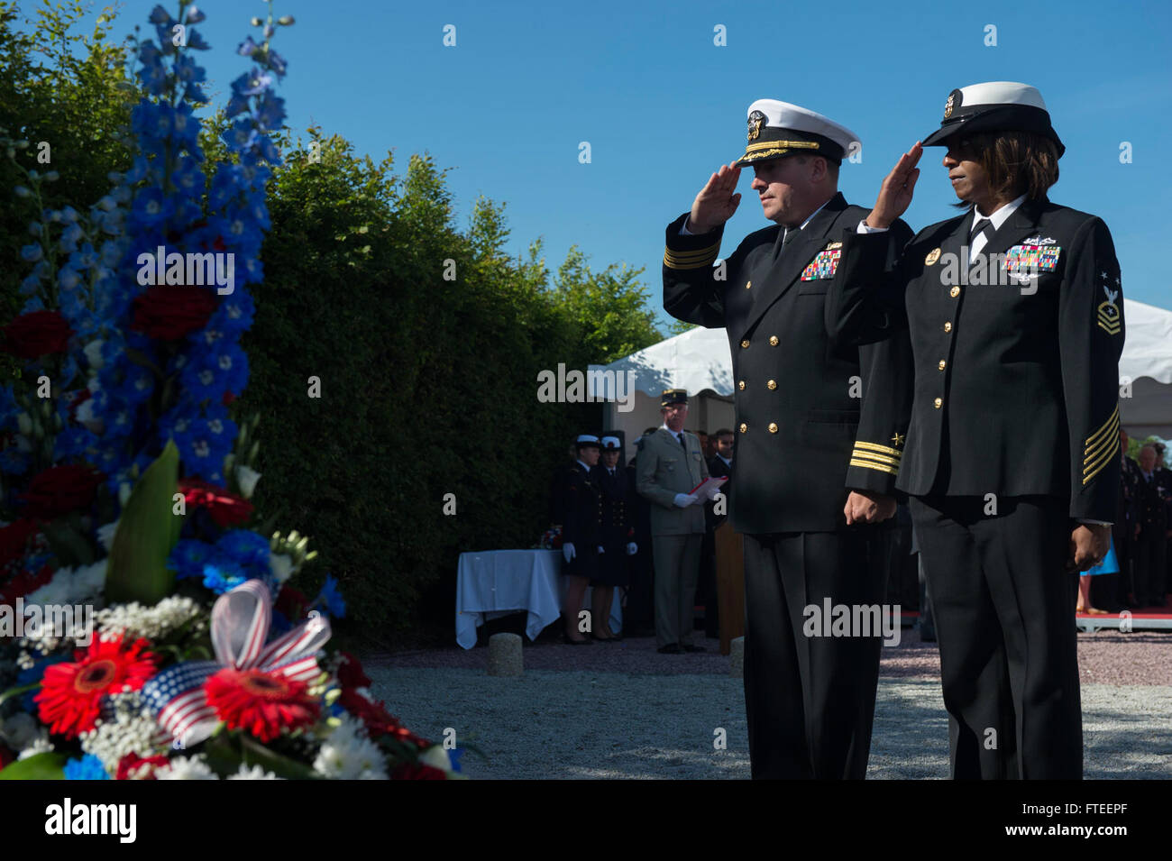 140606-N-YO152-096 UTAH BEACH, France (June 6, 2014) - Cmdr. Brian Diebold, commanding officer of USS Oscar Austin (DDG 79), and CMDCM (SW/AW) Dee Allen render honors after laying down a wreath at the memorial ceremony just off the coast of Utah Beach. The event was one of several commemorations of the 70th Anniversary of D-Day operations conducted by Allied forces World War II June 5-6, 1944. Over 650 U.S. military personnel have joined troops from several NATO nations to participate in ceremonies to honor the events at the invitation of the French government. (U.S. Navy photo by Mass Communi Stock Photo