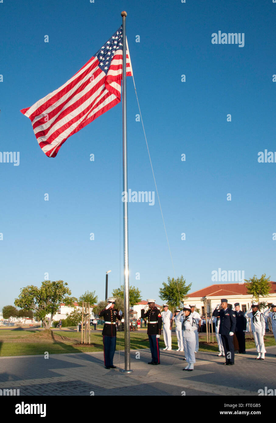 NAVAL STATION ROTA, Spain (July 2, 2015) – Service members assigned to Commander, U.S. Naval Activities Spain, stand at attention and salute the ensign during the annual flag-raising ceremony, July 2. While raising the flag is a daily occurrence on most U.S. military installations around the world, Naval Station Rota is only permitted to fly the American flag with special permission from the base’s Spanish admiral in chief in accordance with the Agreement on Defense Cooperation.  (U.S. Navy photo by Mass Communication Specialist 2nd Class Grant Wamack/Released) Stock Photo