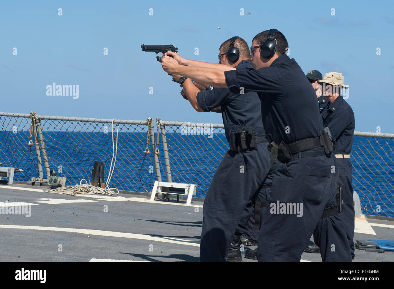 MEDITERRANEAN SEA (October 2, 2014) – Sailors fire 9mm Beretta firearms during small arms qualification training aboard the Arleigh Burke-class guided-missile destroyer USS Cole (DDG 67). Cole, homeported in Norfolk, Va., is conducting naval operations in the U.S. 6th Fleet area of operations in support of U.S. national security interests in Europe. Stock Photo