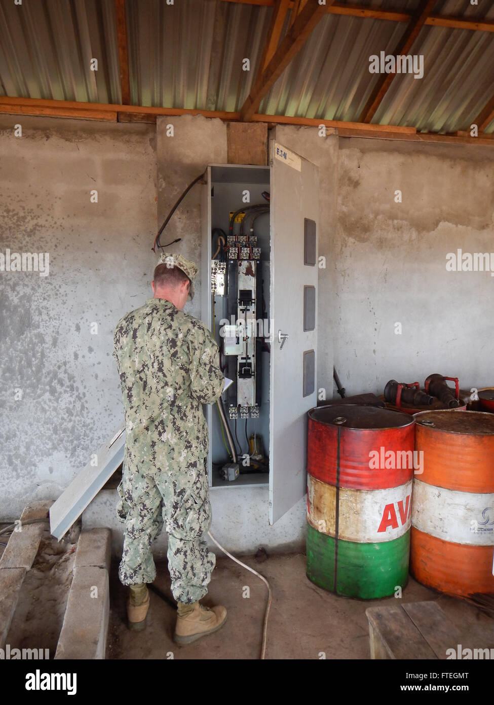 MONROVIA, Liberia (October 4, 2014)  Construction Electrician 2nd Class Matthew Mosley, assigned to Naval Mobile Construction Battalion 133, inspects a power panel to determine if it is repairable during a site assessment in Buchanan, Liberia; a possible site for future berthing of U.S. Forces in support of Operation United Assistance. Stock Photo