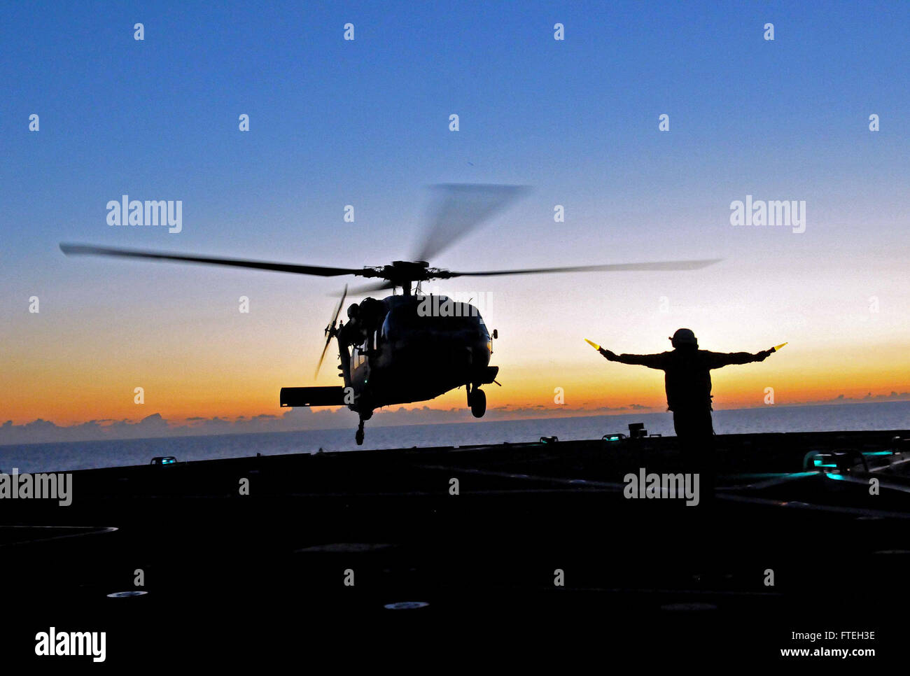 IONIAN SEA (Oct. 09, 2014) A civil service mariner directs an MH-60S Sea Hawk helicopter assigned to the Ghostriders of Helicopter Sea Combat Squadron (HSC) 28 during takeoff from the U.S. 6th Fleet command and control ship USS Mount Whitney (LCC 20). Mount Whitney, homeported in Gaeta, Italy, operates with a combined crew of Sailors and Military Sealift Command civil service mariners. Stock Photo