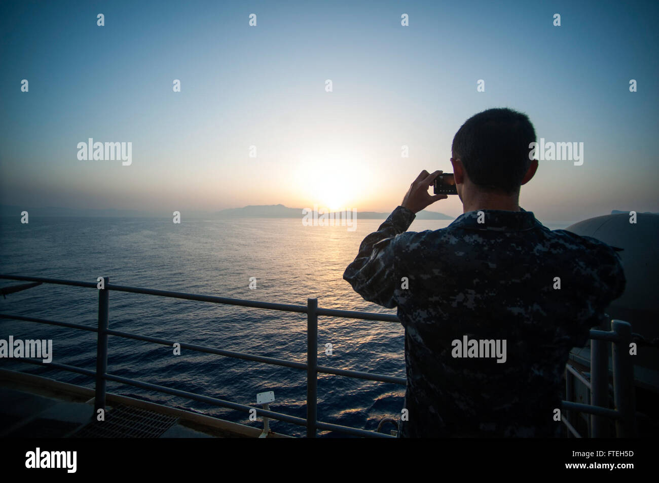 NAPLES, Italy (Oct. 10, 2014) -- A Sailor aboard the amphibious assault ship USS Bataan (LHD 5) takes a sunrise photo prior to pulling into Naples, Italy. The Bataan Amphibious Ready Group is on a scheduled deployment supporting maritime security operations, providing crisis response capability and theater security cooperation efforts in the U.S. 6th Fleet area of operations. Stock Photo