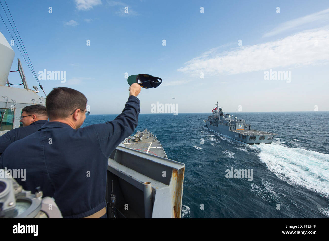 aboard the Arleigh Burke-class guided-missile destroyer USS Cole (DDG 67) waves good-bye to the Turkish navy Barbaros-class frigate TCG Salihreis (F 246) during a passing exercise. Cole, homeported in Norfolk, Va., is conducting naval operations in the U.S. 6th Fleet area of operations in support of U.S. national security interests in Europe. Stock Photo