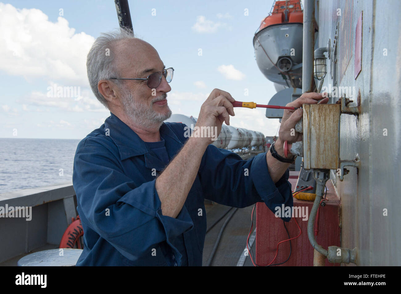 MEDITERRANEAN SEA (Oct. 28, 2014) – Civil service mariner Chief Electrician Jeff Patterson works on the flight deck fire protection system aboard the fleet replenishment oiler USNS Leroy Grumman (T-AO 195). Grumman, the Military Sealift Command Mediterranean Sea duty oiler, is forward-deployed to the U.S. 6th Fleet area of operations in support of national security interests in Europe and Africa. Stock Photo