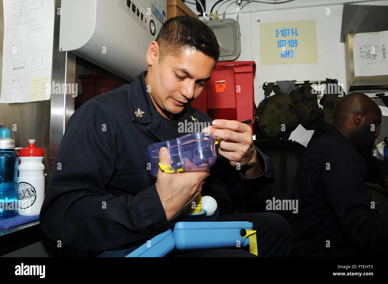 MEDITERRANEAN SEA (Oct. 28, 2014) Hospital Corpsman 1st Class Rejoy Sison, from Milpitas, Calif., practices donning an Emergency Escape Breathing Device (EEBD) aboard the aircraft carrier USS George H.W. Bush (CVN 77). George H.W. Bush, homeported in Norfolk, Va., is conducting naval operations in the U.S. 6th Fleet area of operations in support of U.S. national security interest in Europe. Stock Photo