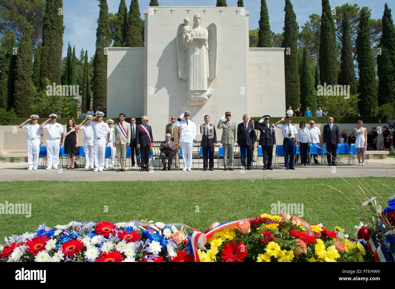 : DRAGUIGNAN, France (August 16, 2013) – Visitors and distinguished guest render honors as the national anthem of the U.S. and France are played during a ceremony at the Rhone American Cemetery in honor of the 69th anniversary celebration of allied troops landing in Provence during World War II. This visit serves to continue U.S. 6th Fleet efforts to build global maritime partnerships with European nations and improve maritime safety and security. Stock Photo