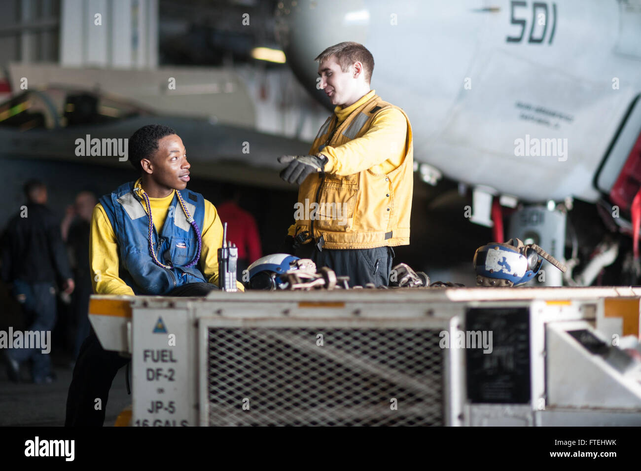 MEDITERRANEAN SEA (Oct. 29, 2014) Aviation Boatswain’s Mate (Handling) Airman Edric Ruffin, from Cleburne, Texas, left, and Aviation Boatswain’s Mate (Handling) Airman Jak Kester, from Orting, Wash., move aircraft in the hangar bay aboard the aircraft carrier USS George H.W. Bush (CVN 77). George H.W. Bush, homeported in Norfolk, Va., is conducting naval operations in the U.S. 6th Fleet area of operations in support of U.S. national security interests in Europe. Stock Photo