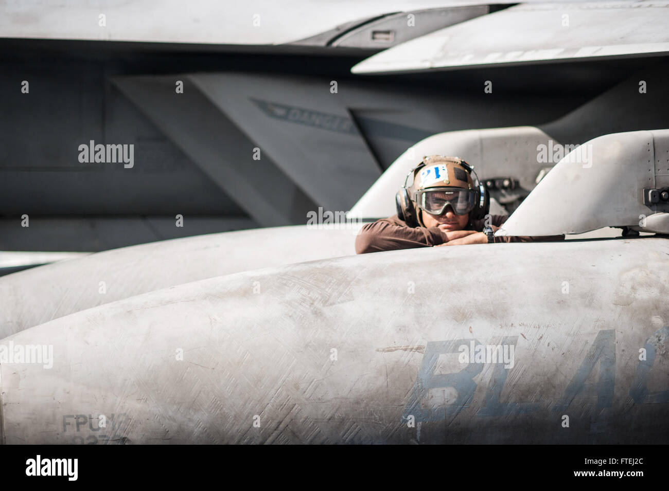 Aviation Electronics Technician Airman Trinidad Silva, from San Jose, California, is seen resting on a fuel tank of an F/A-18F Super Hornet aboard the USS George H.W. Bush. The aircraft carrier is operating in the Mediterranean Sea as part of U.S. naval operations supporting national security interests. Stock Photo