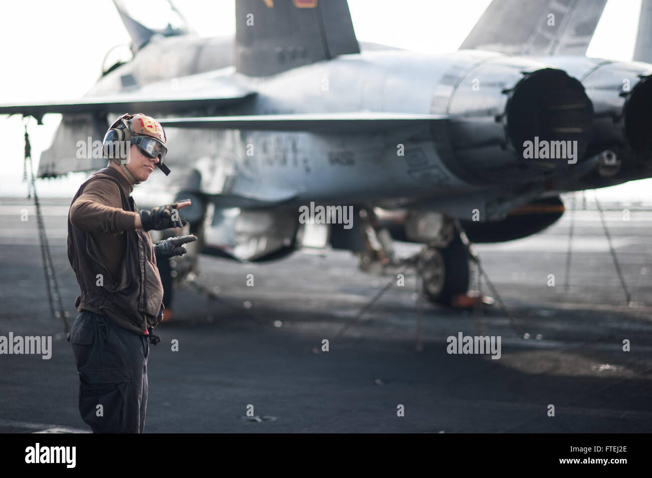 MEDITERRANEAN SEA (Oct. 31, 2014) Aviation Structural Mechanic Airman London Olan, from Toledo, Ohio, stands by as a safety observer as an F/A-18C Hornet, attached to the &quot;Golden Warriors&quot; of Strike Fighter Squadron (VFA) 87, conducts a low power turn on the flight deck of the aircraft carrier USS George H.W. Bush (CVN 77). George H.W. Bush, homeported in Norfolk, Va., is conducting naval operations in the U.S. 6th Fleet area of operations in support of U.S. national security interests in Europe. Stock Photo