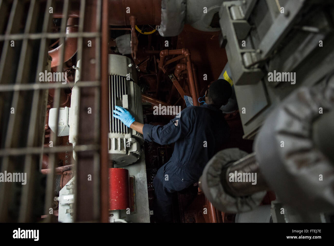 MEDITERRANEAN SEA (November 10, 2014) – Fireman George Karuru, from Kenya, conducts a visual inspection of the lower half of a main reduction gear aboard the USS Cole (DDG 67). Cole is an Arleigh Burke-class guided-missile destroyer, homeported in Norfolk, Va., conducting naval operations in the U.S. 6th Fleet area of operations in support of U.S. national security interests in Europe. Stock Photo