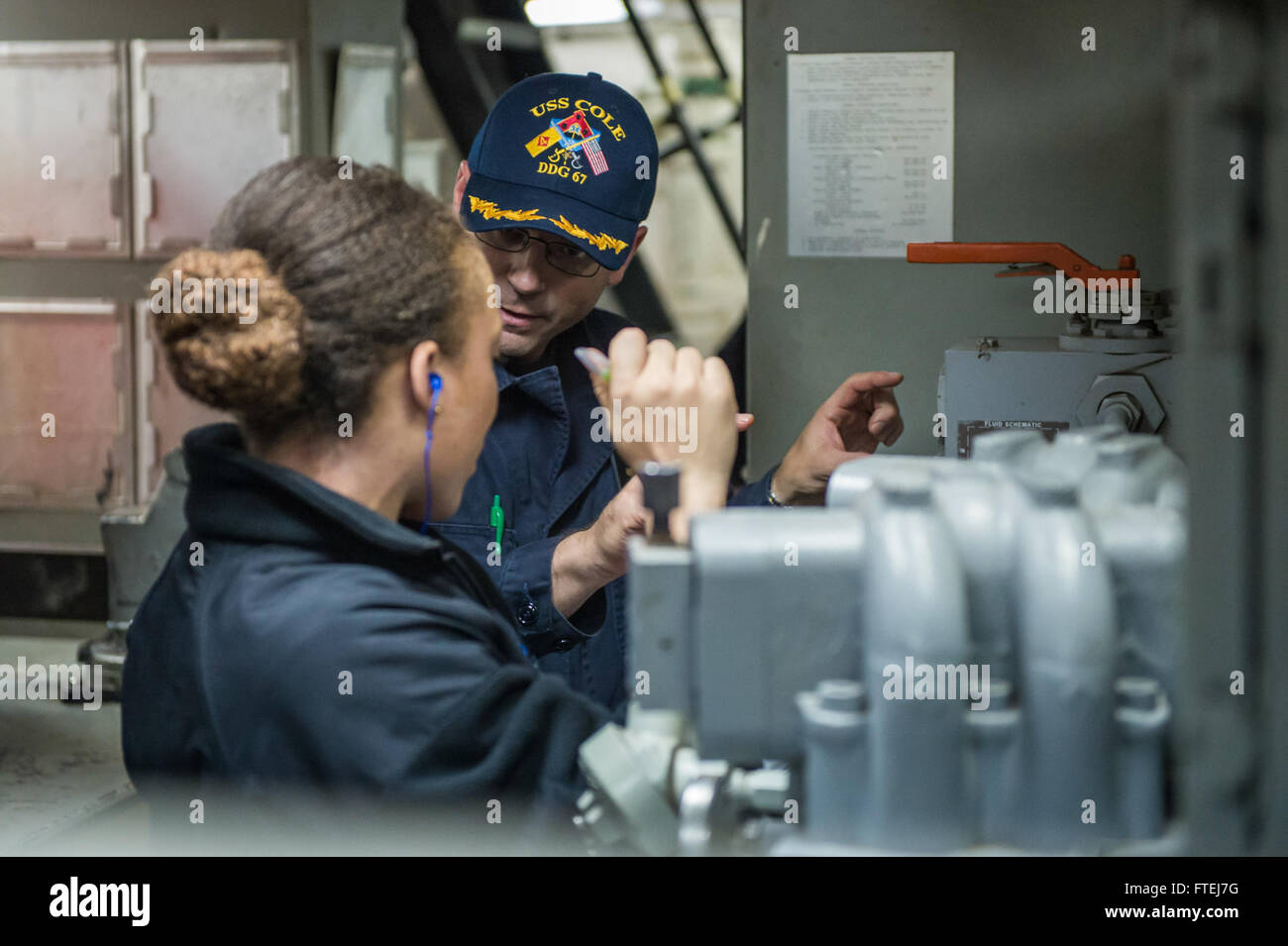 MEDITERRANEAN SEA (November 10, 2014) – Cmdr. James Quaresimo, from Norfolk, explains propulsion fundamentals to Ensign Tamarah Ware, from Norfolk, aboard the USS Cole (DDG 67). Cole is an Arleigh Burke-class guided-missile destroyer, homeported in Norfolk, Va., conducting naval operations in the U.S. 6th Fleet area of operations in support of U.S. national security interests in Europe. Stock Photo