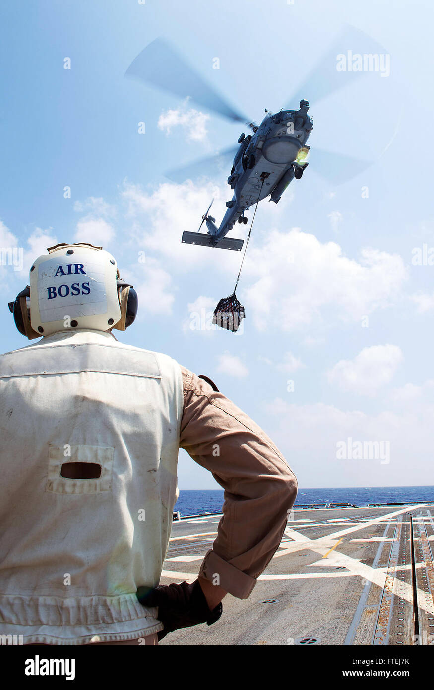 MEDITERRANEAN SEA (Aug 18, 2013) Ð Lt. Cmdr. John Nadder, Air Boss, from Richmond, Va., watches as a SH-60 R Seahawk prepares to drop supplies during a vertical replenishment-at-sea (VERTREP) with Military Sealift Command oiler USNS Leroy Grumman (T-AO 195) aboard the guided missile destroyer USS Gravely (DDG 107). Gravely, homeported in Norfolk, Va., is on a scheduled deployment supporting maritime security operations and theater security cooperation efforts in the 6th Fleet area of responsibility. Stock Photo
