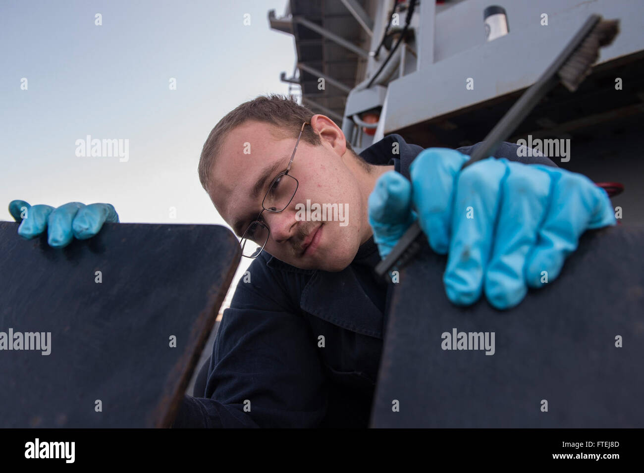 MEDITERRANEAN SEA (Nov. 12, 2014) – Gunner’s Mate Seaman James Lumbley, from Livingston, Texas, conducts periodic maintenance on a .50-caliber machine gun mount aboard USS Cole (DDG 67). Cole, an Arleigh Burke-class guided-missile destroyer, homeported in Norfolk, is conducting naval operations in the U.S. 6th Fleet area of operations in support of U.S. national security interests in Europe. Stock Photo