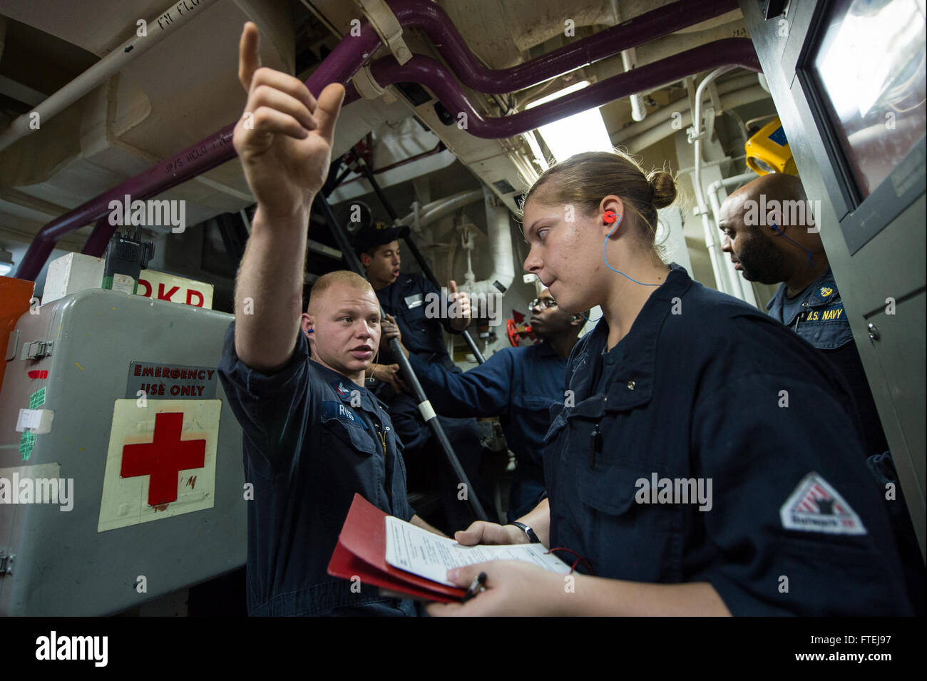 MEDITERRANEAN SEA (Nov. 14, 2014) – Machinist Mate 2nd Class Nicholas Ross, from Rochester, New York, explains the importance of delegation of steps to other engineers during an emergency shut down to Gas Turbine System Mechanical Fireman Samantha Stapp, from Olathe, Kansas, during an engineering drill aboard USS Cole (DDG 67). Cole an Arleigh Burke-class guided-missile destroyer homeported in Norfolk, is conducting naval operations in the U.S. 6th Fleet area of operations in support of U.S. national security interests in Europe. Stock Photo