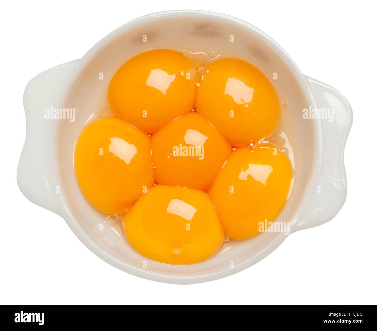 Six raw egg yolks in a white bowl Stock Photo