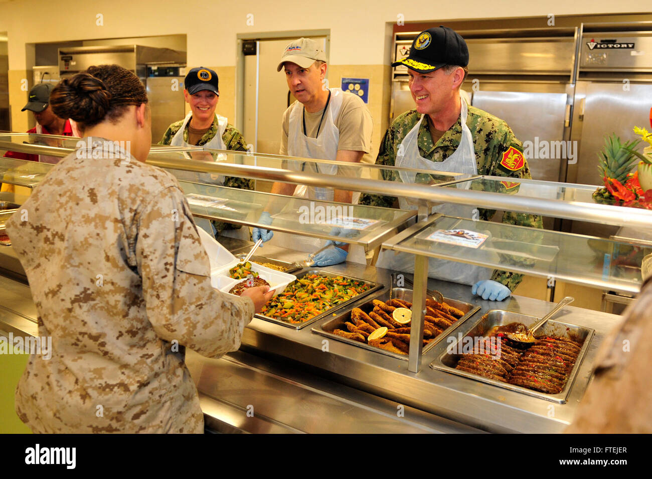 CAMP LEMONNIER, Djibouti (Nov. 27, 2014) Adm. Mark Ferguson, commander, U.S. Naval Forces Europe-Africa (right), U.S. Ambassador to Djibouti, Tom Kelly (center), and Fleet Master Chief JoAnn Ortloff (left), serves Thanksgiving lunch at Camp Lemonnier. Ferguson visited Camp Lemonnier to thank Sailors for supporting forward U.S. forces and for strengthening security in East Africa. Stock Photo