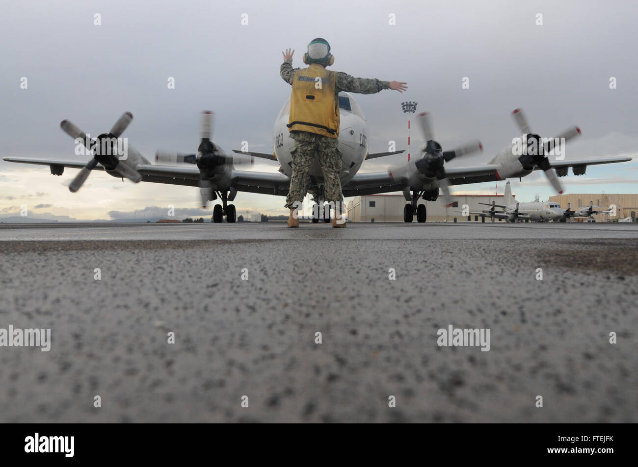 SIGONELLA, Sicily (Dec. 3, 2014) Aviation Electronics Technician 2nd Class Spencer Bean signals a P-3C Orion maritime patrol aircraft belonging to Patrol Squadron (VP) 4, Dec. 3, 2014. VP 4 is conducting naval operations in the U.S. 6th Fleet area of operations in support of U.S. national security interests in Europe. Stock Photo