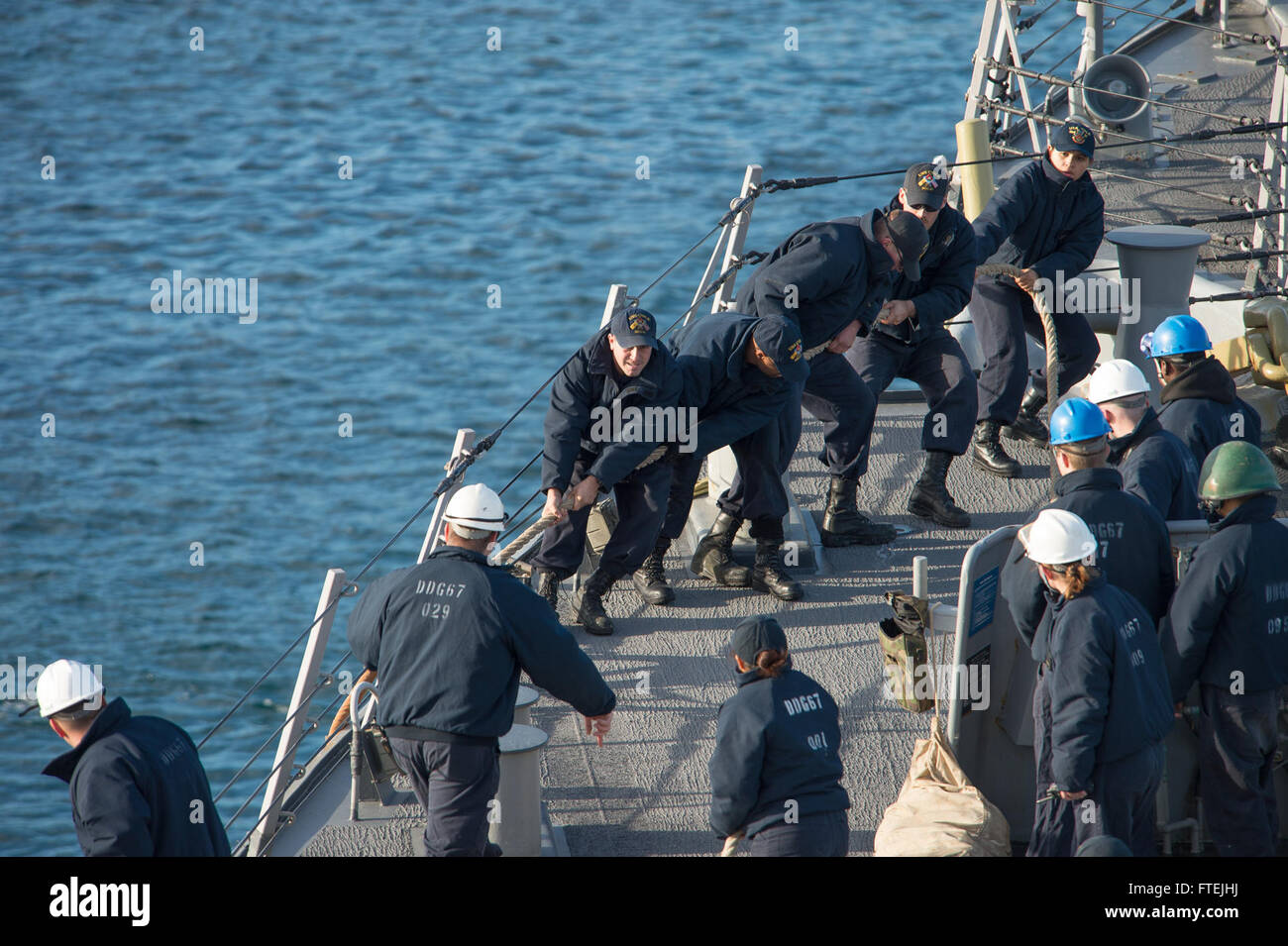 AUGUSTA BAY (Dec. 8, 2014) Sailors aboard USS Cole (DDG 67) heave in mooring lines as the ship pulls in to Augusta Bay, Sicily, during a scheduled port visit Dec. 8, 2014. Cole, an Arleigh Burke-class guided-missile destroyer, homeported in Norfolk, is conducting naval operations in the U.S. 6th Fleet area of operations in support of U.S. national security interests in Europe. Stock Photo